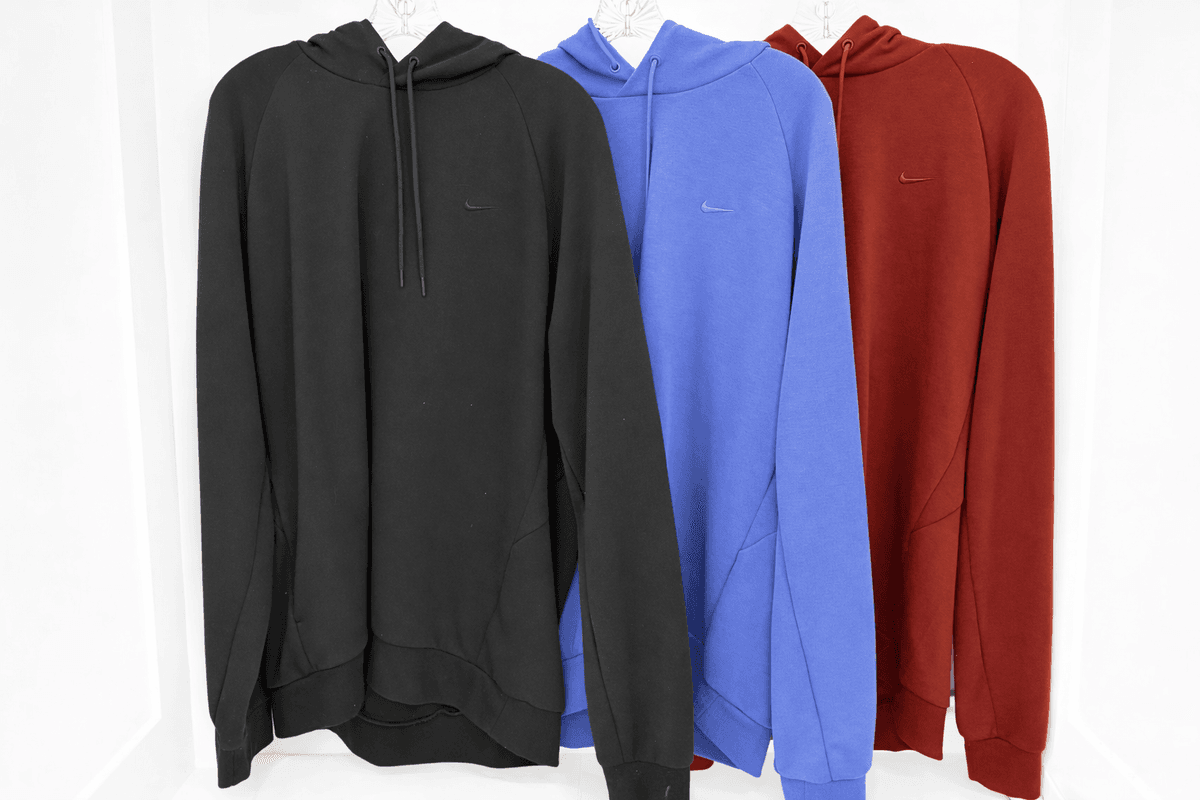 Three Nike Dri-FIT performance sweatshirts hanging side by side in black, royal blue and dark red